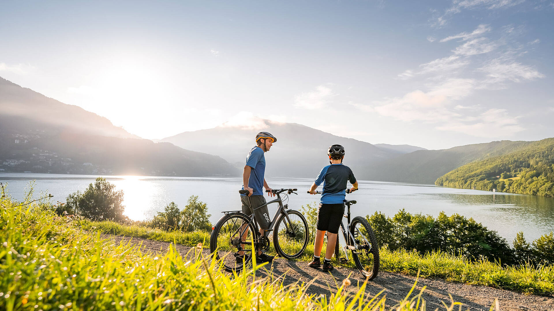 Radfahrer am Millstätter See machen Pause und genießen den Blick auf den See